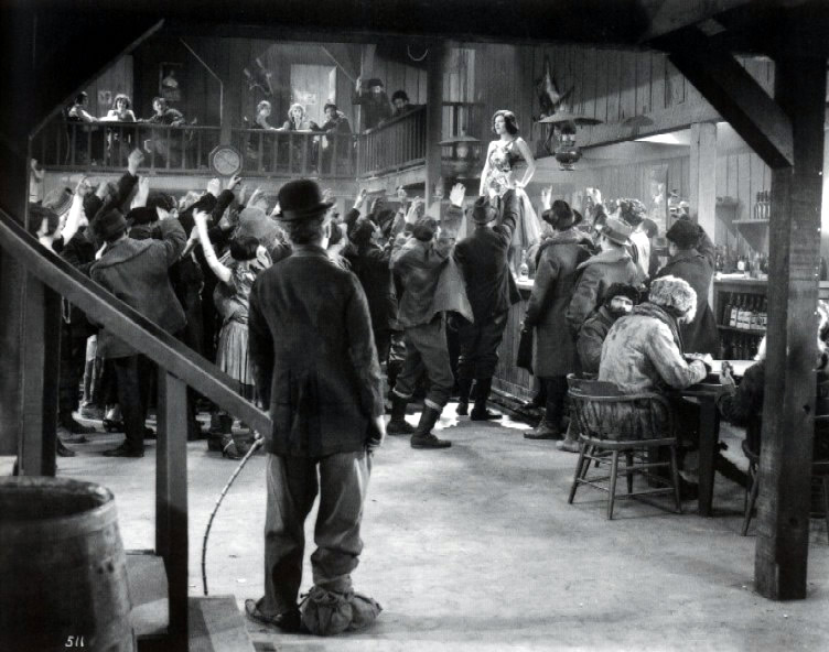 Klondike Saloon scene. Chaplin puts the camera below eye level, silhouetting his own figure so that both he and Georgia ( Georgia Hale ) stand apart.