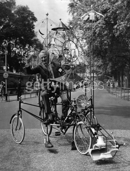 ''Cartoonist and inventor Rowland Emett rides his "lunacycle" invention. The lunacycle's "scientific refinements" allow it to be soft landed on the moon. Its features include a cat for companionship and for catching moon mice, and a fly-swatter rig for keeping meteorites at bay and shielding the instruments from the rays of the sun. London, England, June 11, 1970.''