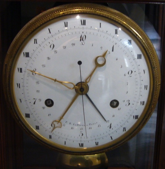 ''The single long hand with a circle at one end and a point at the other probably shows the hours in both old and new systems. One end points to the decimal time, with 10 (0) being midnight, and 5 being midday, the other end to the equivalent old-style time. Presumably, therefore, old-style midnight (XII) is at the bottom of the dial, so that the other end can point to 10 (0). 1 o’clock (decimal) is about 02:20 old style, and the position of the hour hand in this photograph suggests that the time is 0.90 (d), or 02:10 old style.''